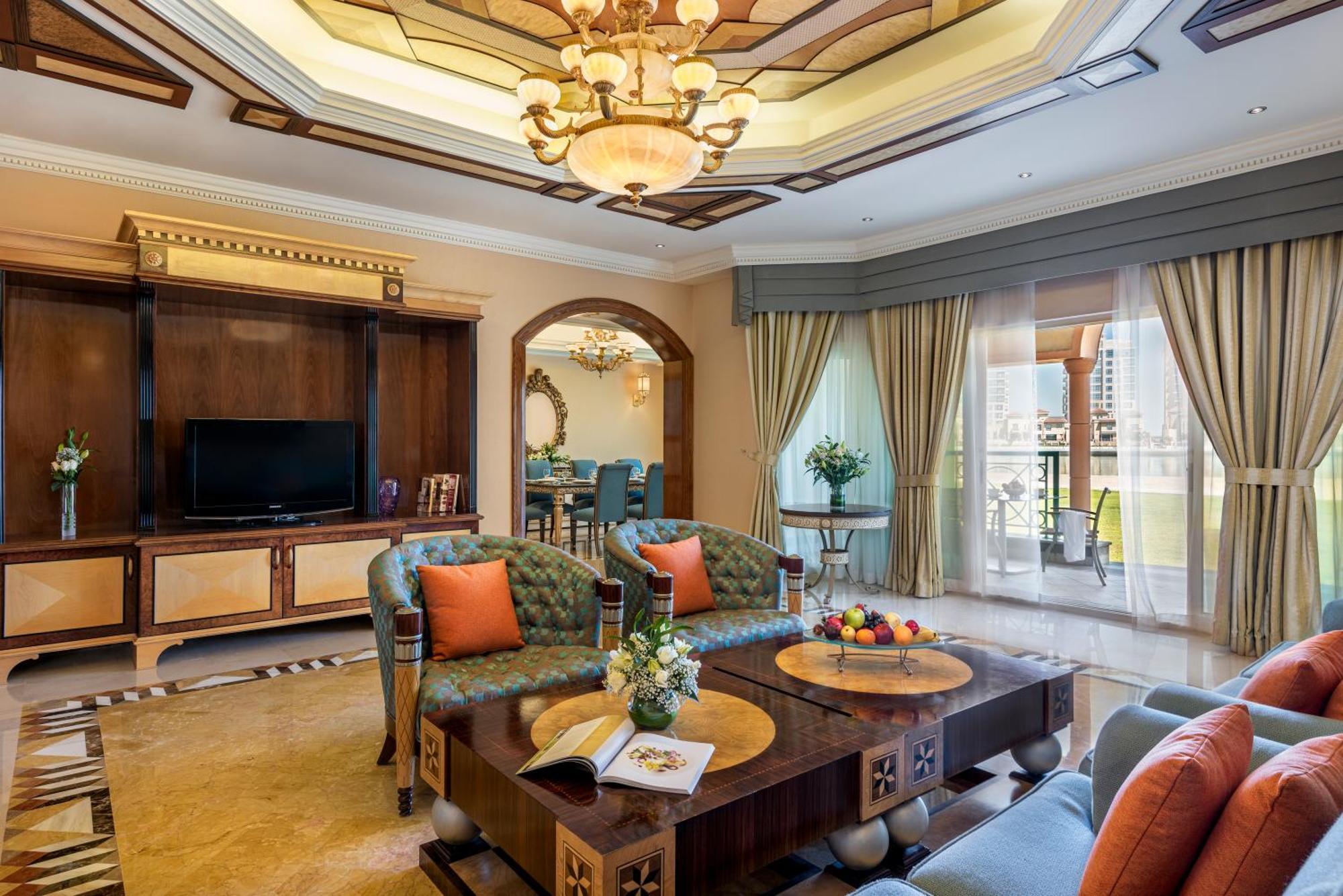 Al Raha Beach Resort & Spa Abu Dhabi Esterno foto The photo depicts a luxurious living room with elegant decor. It features two green upholstered sofas accented with orange pillows, arranged around a stylish coffee table. The coffee table showcases decorative items, including a magazine and a bowl o